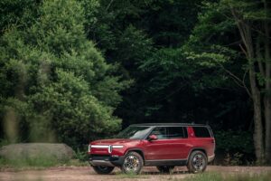 Электрический внедорожник Rivian R1S 2022 преодолевает глубокую лужу на бездорожье, демонстрируя проходимость