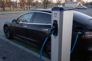 Tesla Model 3 2022 заряжается на станции Supercharger. Зарядка электромобиля, сеть быстрых зарядных станций Тесла.